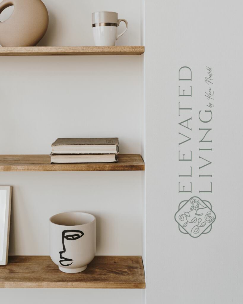 A bookcase with books and mugs on it built into a wall. On the side of the wall is a logo that says "Elevated Living by Kara Neufeld"
