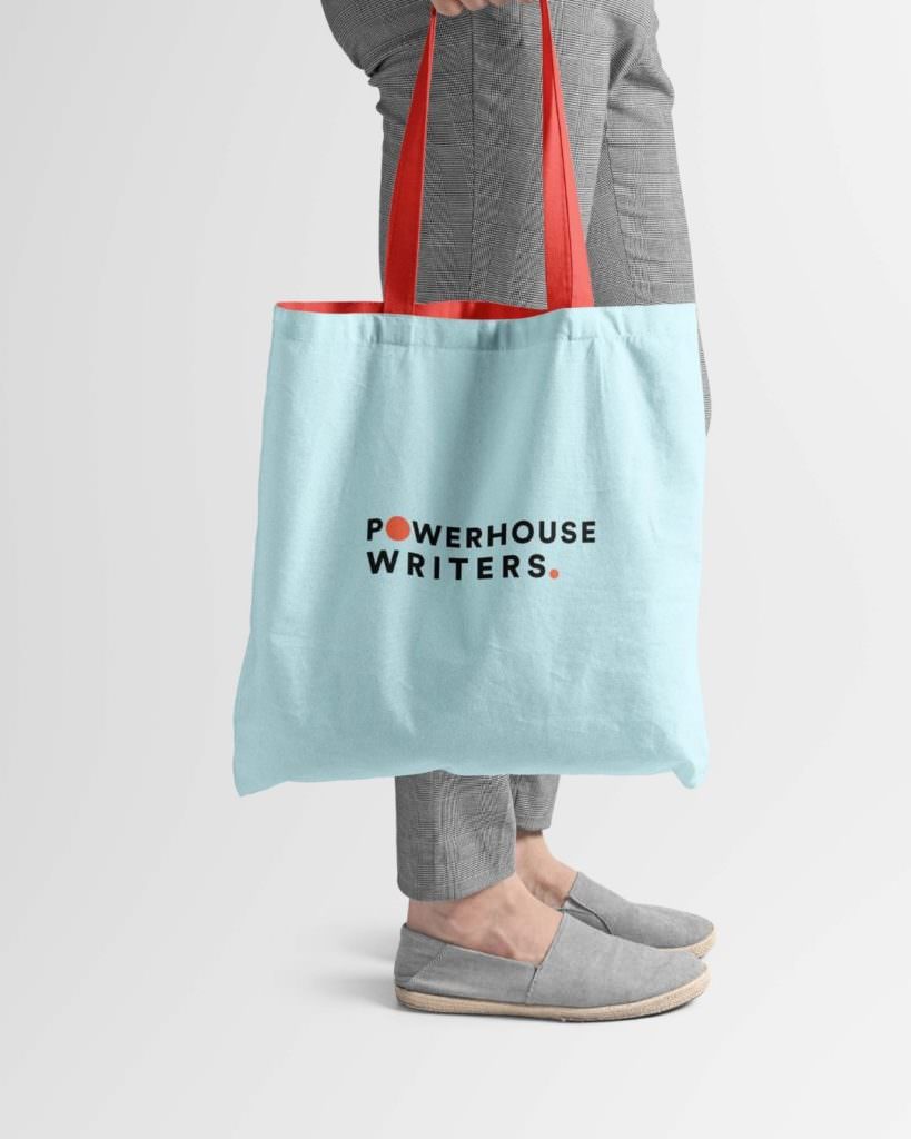 Person holding a colorful tote bag that says "Powerhouse Writers" on the front.