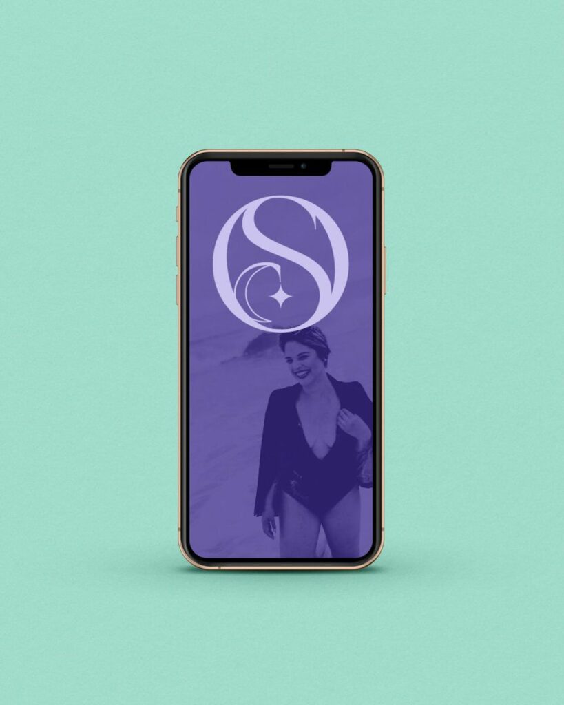 A phone standing up against a mint backdrop with a purple logo pulled up on the screen. 