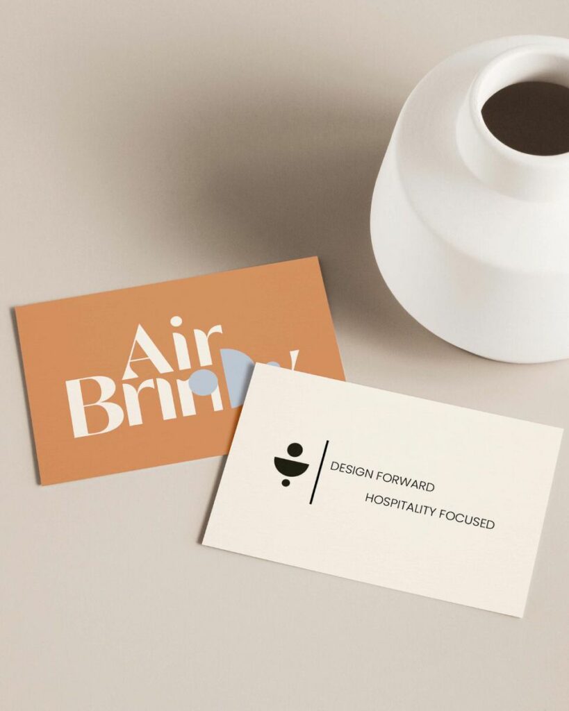 Two business cards slightly overlapping with a small vase next to them.