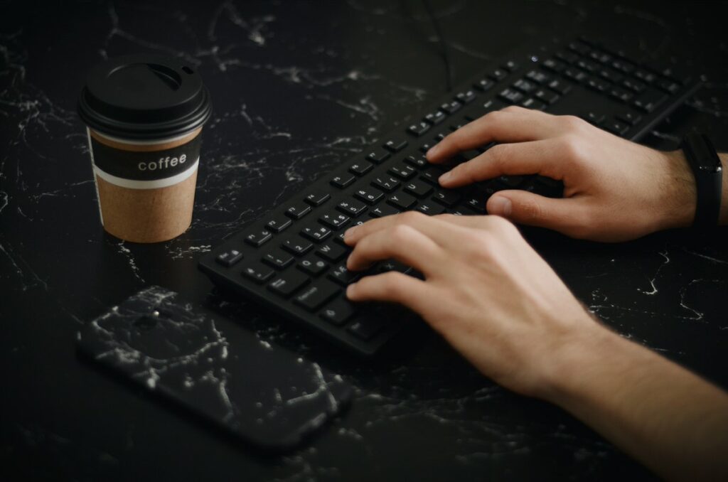 A close up image of hands typing on a black keyboard. 