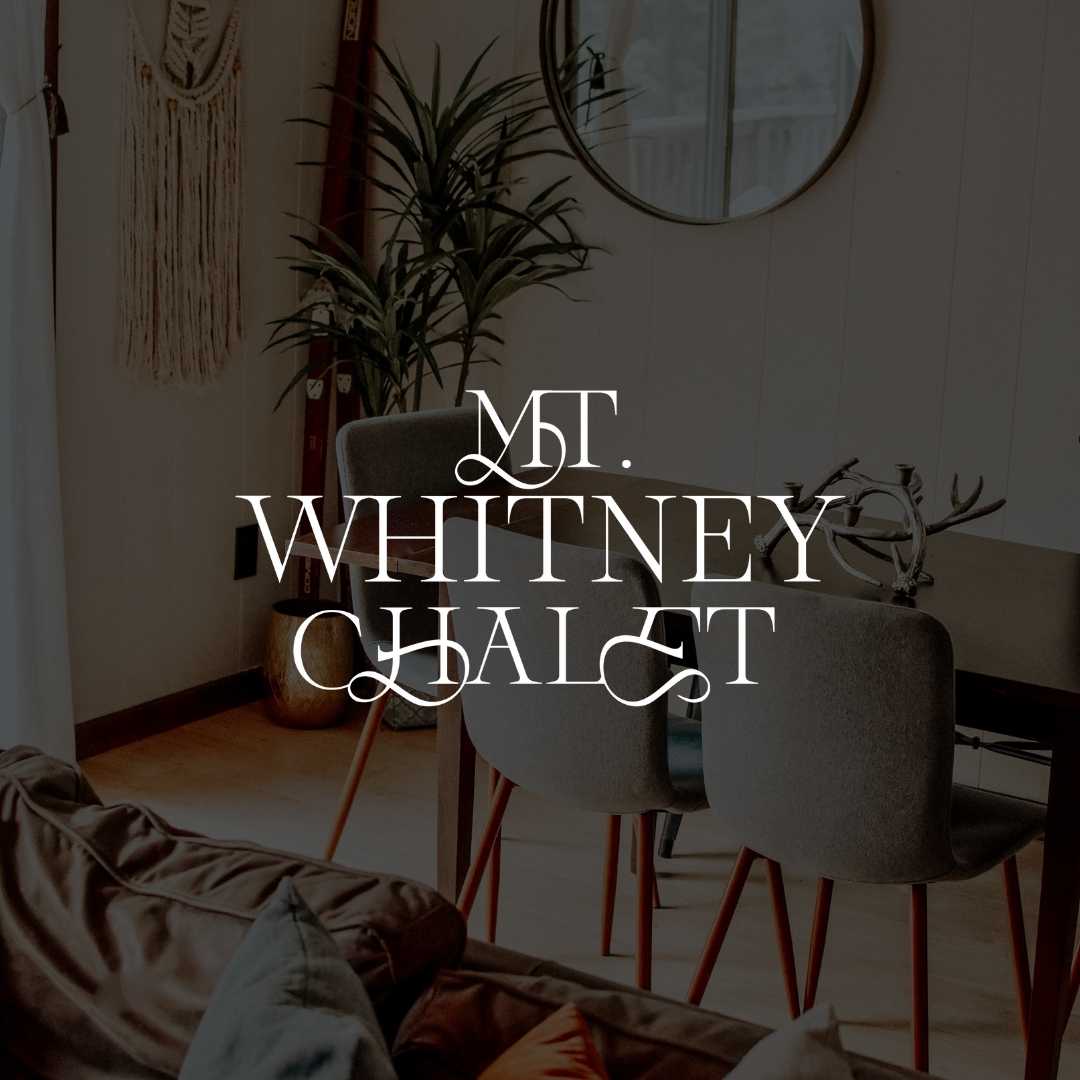 Image of a dining room in a small home with a dark overlay on the image. On top is a white logo that reads "Mt Whitney Chalet".