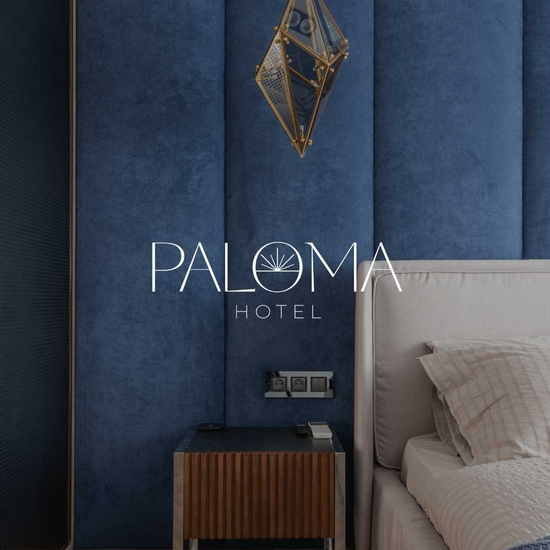 Image of a bedside table in a luxury hotel with a logo on top for Paloma Hotel.