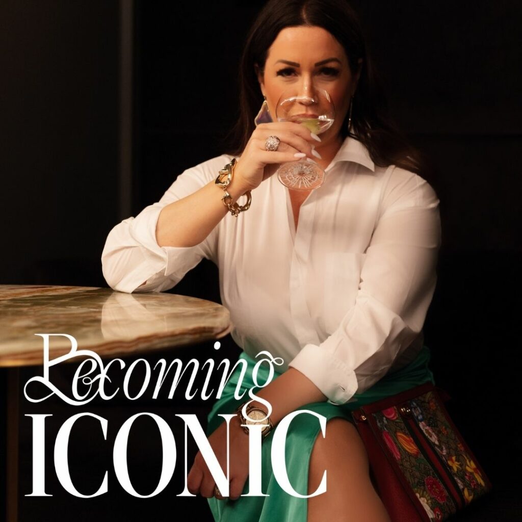 Woman sitting at a table drinking out of a glass with a logo in the bottom left corner that read "Becoming Iconic".