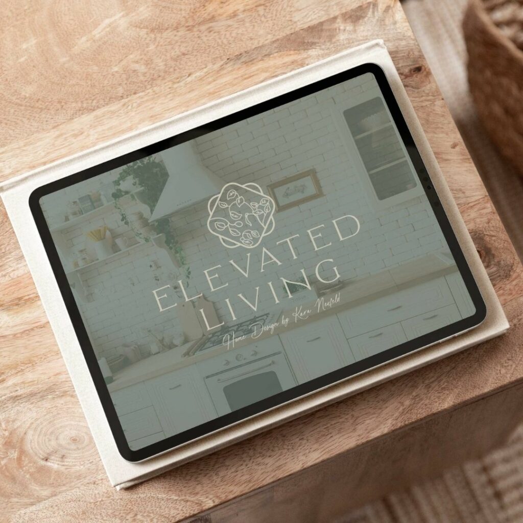 An iPad sitting on the corner of a table with a logo pulled up on the screen that says "Elevated Living. Home Design by Kara Neufeld".