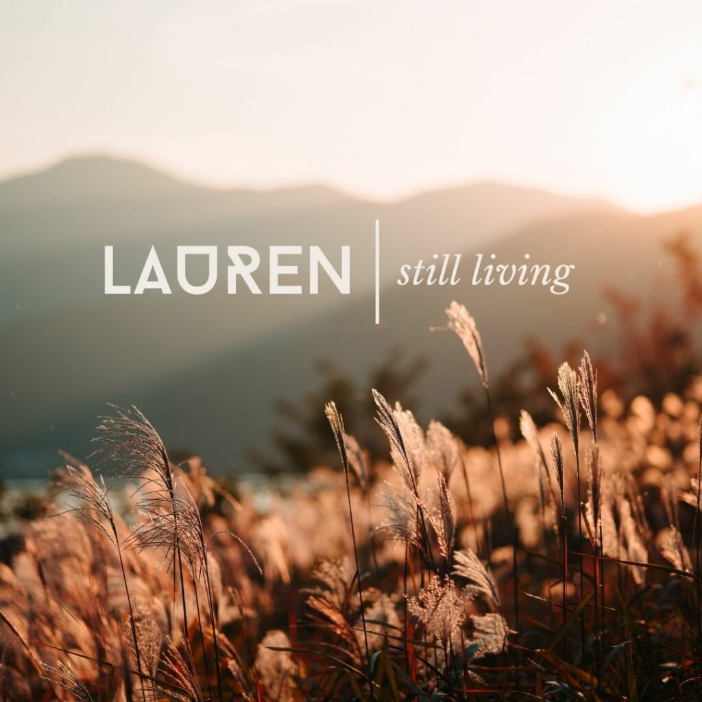 A close up image of tall grass in a field at sunset with a logo on top that says "Lauren | still living" 