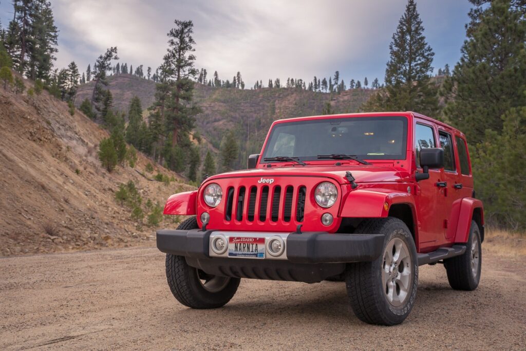 Red Jeep parked on a dirt road in the mountains. 