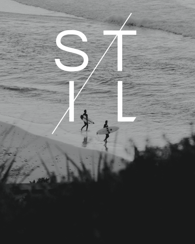 Black and white aerial image of two surfers running into the water with a white logo over the image that says "Stil"