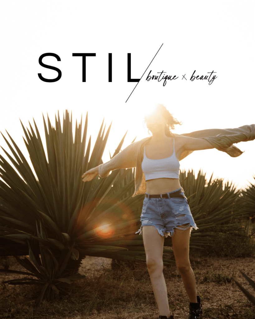 woman with her arms outstretched walking outside at sunset with a logo on the top of the image that says "Stil boutique + beauty"