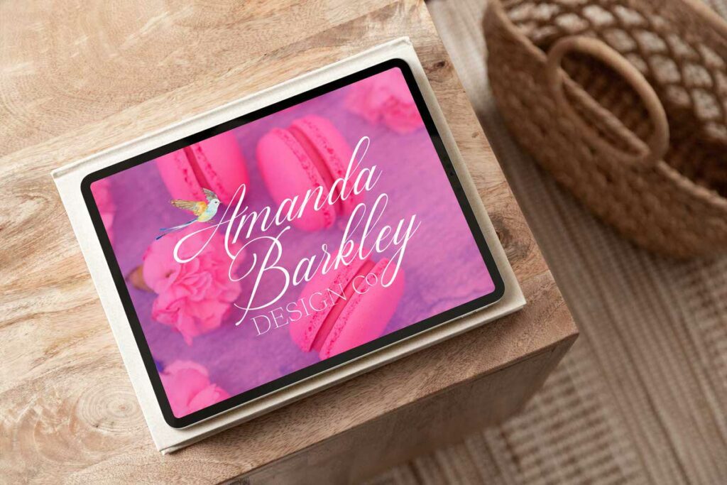 iPad sitting on the corner of a wooden table with an image pulled up of macaroons with a logo on top that says "Amanda Barkley Design Co". 