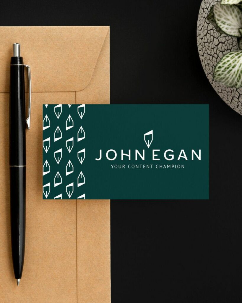 A business card for John Egan on a desk with a pen next to it. 
