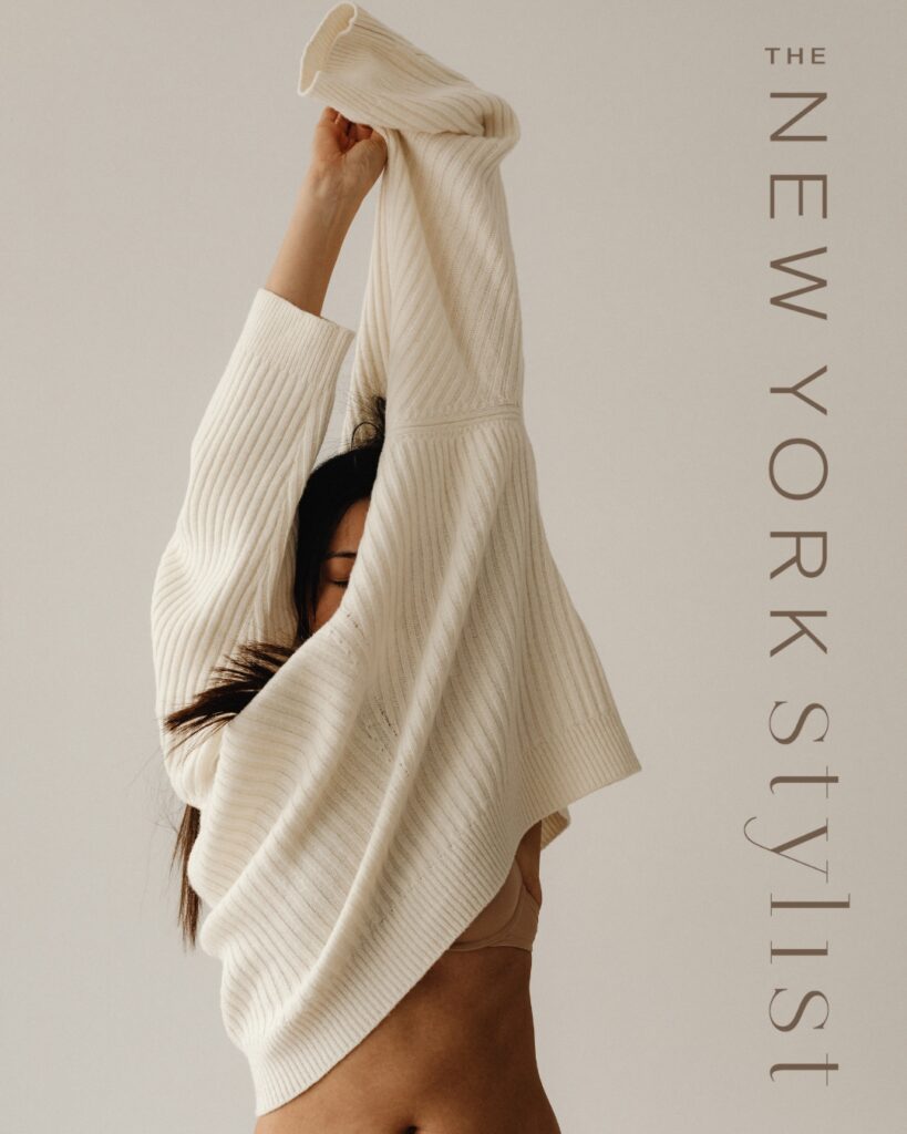Artistic promotional image for The New York Stylist, featuring a woman holding a sweater over her head, giving a sense of movement and transformation associated with fashion styling.