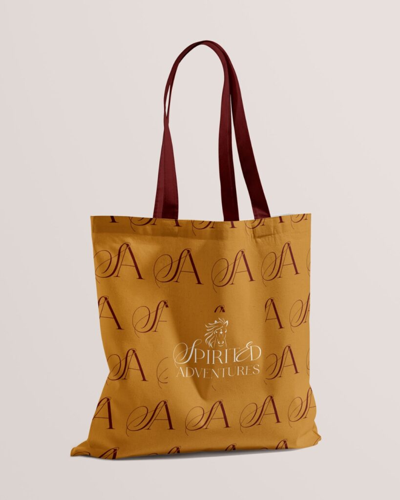 A stylish tote bag in mustard color with the 'Spirited Adventures' logo patterned all over, showcasing brand identity.