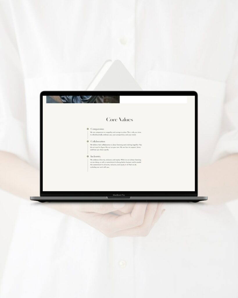 A minimalist website design on a laptop screen held by hands, detailing core values of compassion, collaboration, and exclusivity in a clean and elegant font.