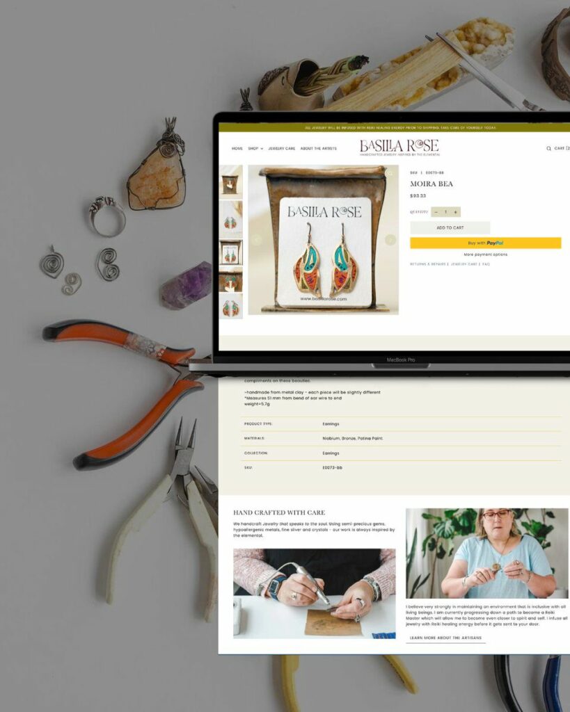 An assortment of jewelry-making tools and handcrafted jewelry pieces laid out around a MacBook displaying the Basilia Rose jewelry website with a featured pair of earrings